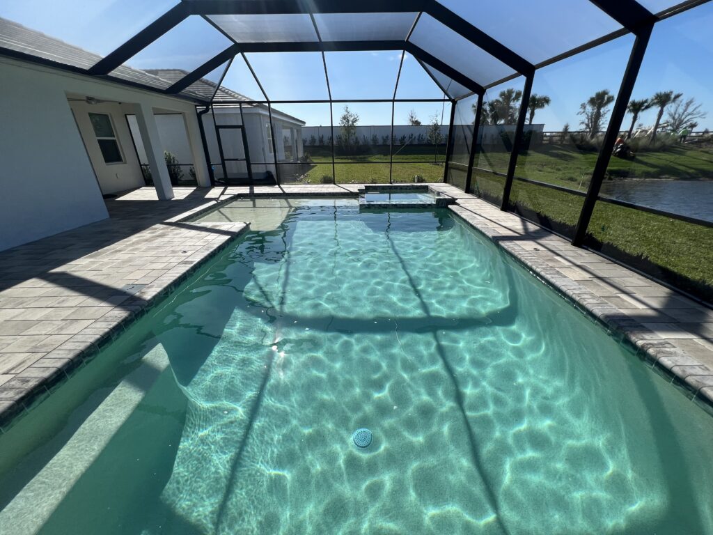 Clear screened-in backyard pool in the sunshine